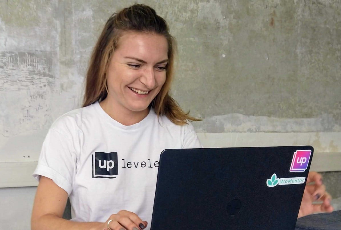 Alena coding at her laptop wearing an UpLeveled shirt