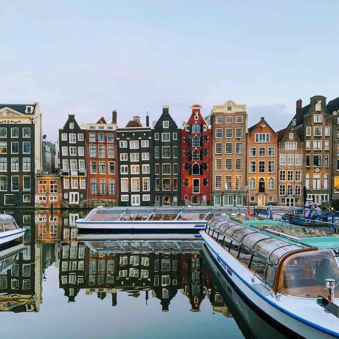 Amsterdam canal with tourist boats and traditional house facades