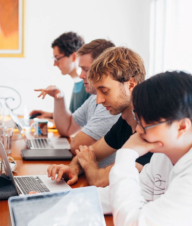 Diverse group of young men studying at laptops