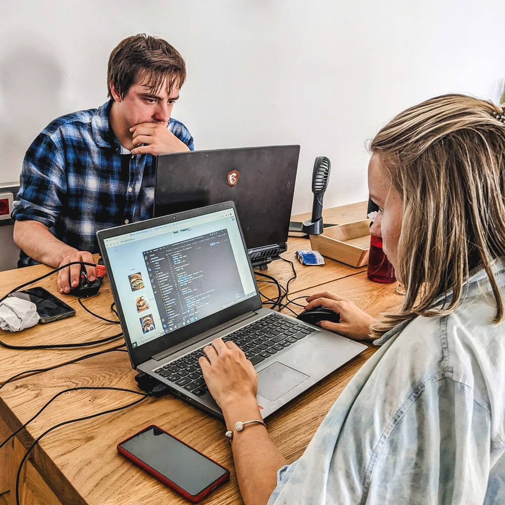 Two participants work side by side on laptops during a training session