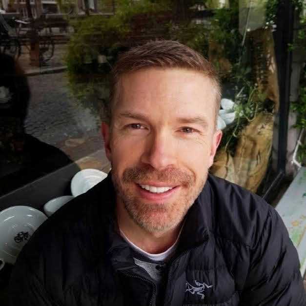 White man sitting in front of a cafe window